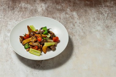 Izgarada kızartılmış patates, pırasa, kırmızı biber, kırmızı biber ve kiraz domatesleri. Sebzeler kumaş arka planında açık seramik bir tabakta yatıyor..