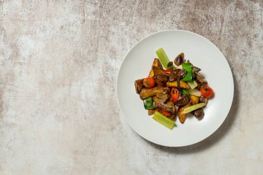 Izgarada kızartılmış patates, pırasa, kırmızı biber, kırmızı biber ve kiraz domatesleri. Sebzeler kumaş arka planında açık seramik bir tabakta yatıyor..