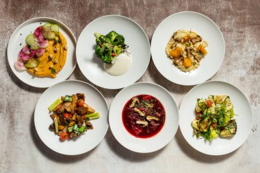 Sebzeli yağsız Ukrayna yemekleri. Yiyecek, kumaş arka planındaki hafif seramik tabaklarda yatıyor..