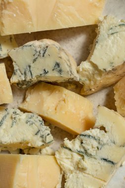 Ukrayna parmesan peyniri ve dorblyu peyniri parçalanmış ve seramik bir tabakta açık kumaş arka planda yatıyor..