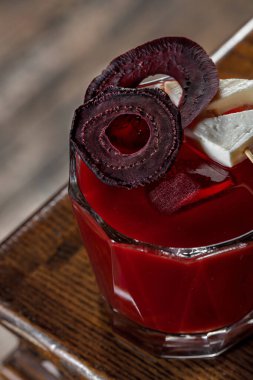 Kanlı Mary kokteyli, pancar suyu, keçi peyniri parçaları ve pancar cipsi masanın köşesindeki siyah ahşap tezgahta duruyor..