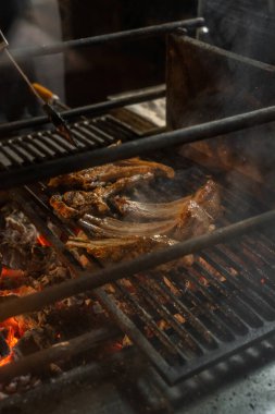Bir kaç parça kuzu pirzola kızgın kömürlerin üzerinde metal ızgarada yatıyor..