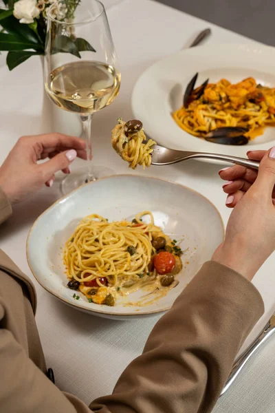 Kaparili ev yapımı spagetti, vişneli domates, humus ezmesi ve hafif bir masa örtüsü üzerinde rendelenmiş parmesan peyniri..