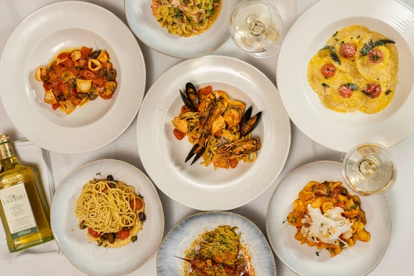 薄めのテーブルクロスに魚介類や野菜とパスタの異なる種類の盛り合わせ皿 — ストック写真