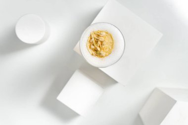 Narenciye köpüklü ve altın yapraklı kokteyl penisilini diğer alçı figürleri arasında bir alçı figürünün üzerinde duruyor. Tüm ögeler beyaz arkaplanda.