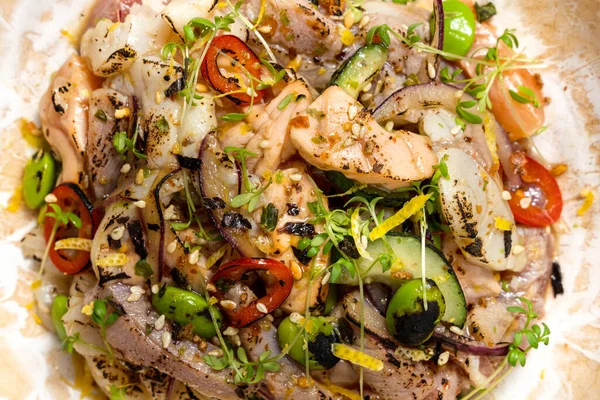 Stock image Rice with seafood, tuna, squid, salmon, green beans, leeks and microgreen sprouts. Food lies in a brown ceramic plate on a black and white paper background. Next to the plaster figure.