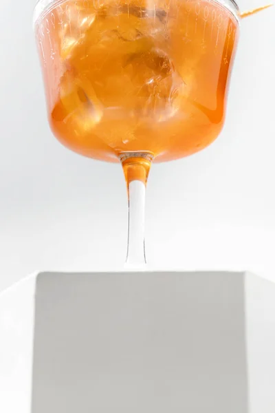 Aperol Spritzは 透明な茎ガラスの中に氷のキューブとキュウリのスライスを入れたカクテルです カクテルは白い背景の他の石膏像の間で石膏像に立っています — ストック写真