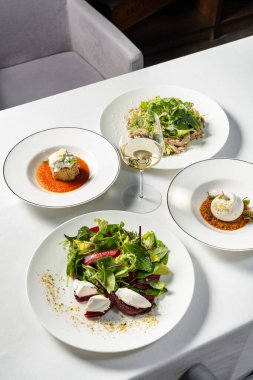 Sebze yahnili Mozzarella ve stracciatella peynirli patlıcan, tavuk salatası ve pancar salatası. Tabaklar hafif bir masa örtüsünün üzerinde seramik tabaklarda yatıyor..