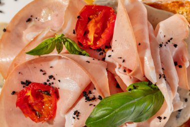 Jambonlu Brioche tostu ve fesleğen yaprağı ve bitkilerle kaplı ceviz sosu. Tost hafif bir seramik tabakta, yanında bir bardak beyaz şarap var..