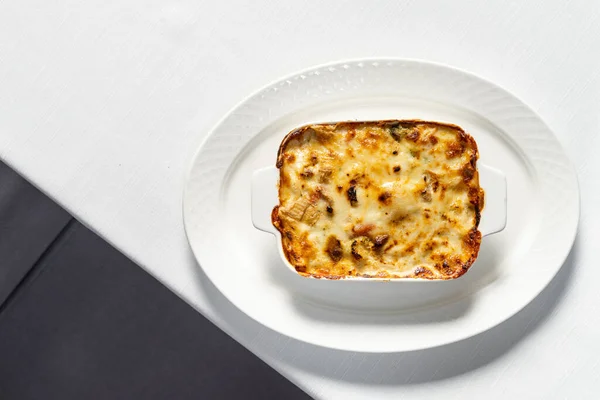 上にすりおろしたパルメザンチーズとセラミック料理で自家製ラザニア 皿はテーブルの上にテーブルクロスがあります — ストック写真