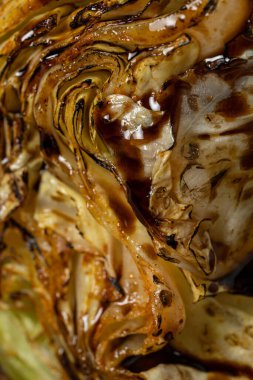 Üç parça fileminyon biftek ızgarada, tahta bir tahtanın üzerinde yatıyor. Yakınlarda balzamik soslu ızgara lahana ve vişne soslu bir kase var. Tahta hafif bir arkaplanda yatıyor.