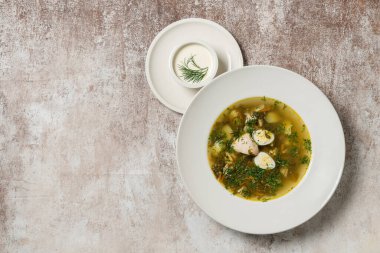 Ukrayna çorbası yeşil borsch hindi eti ve bıldırcın yumurtası seramik tabakta. Yanında bir kase ekşi krema var..