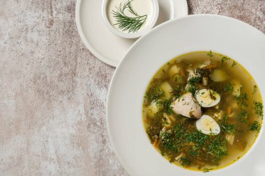 Ukrayna çorbası yeşil borsch hindi eti ve bıldırcın yumurtası seramik tabakta. Yanında bir kase ekşi krema var..