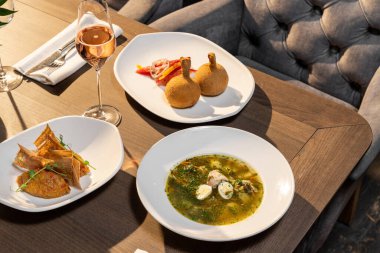 Ukrayna yemeği, Kiev pirzolası, ahşap bir masada seramik tabakta. Yanında bir bardak gül şarabı, bir tabak yeşil borş ve patlıcan havyarı var..