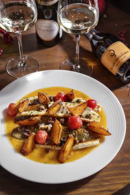 Kızarmış patatesli fileto, zeytin ve sos masada bir şişe ve bir bardak şarapla birlikte.