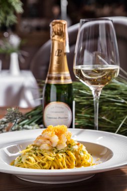 Masada balık, salata ve peynirli makarna bir şişe şarap ve bardakla.