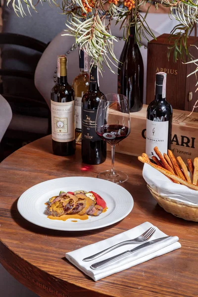 コショウ ズッキーニ ソースとワイングラス カトラリー グリッシーニのバスケットとテーブルの上に立っているワインのボトルとプレート — ストック写真