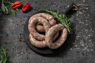 Dijon hardallı biftek sosisi. Siyah, ahşap, yuvarlak bir tahtanın üzerinde yatıyorlar. Tabaklar karanlık bir taşın üzerinde duruyor, baharatlar ve bitkiler etrafa saçılmış..