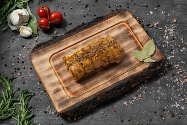 Körili ve otlu salamura edilmiş tavuk dürümü. Açık tahta bir tahtanın üzerinde duruyor. Tabaklar karanlık bir taşın üzerinde duruyor, baharatlar ve bitkiler etrafa saçılmış..