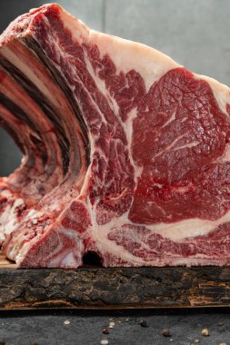 Hafif ahşap bir tahtanın üzerinde, tuzlu ve biberli bezelyelerle karışık koyu taştan bir zemin üzerinde duran bir parça et..