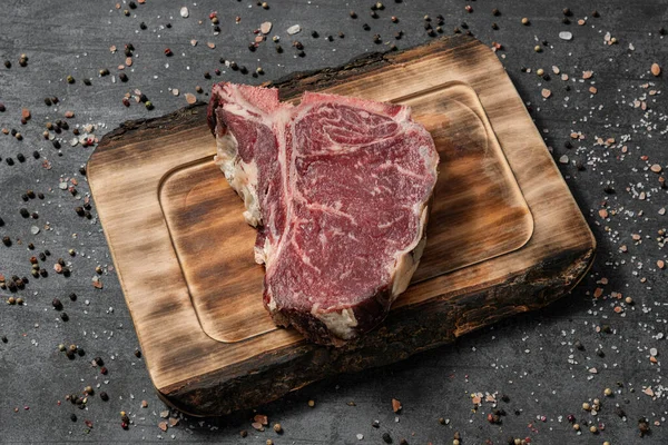 Bone Steak Auf Einem Hellen Holzbrett Stehend Auf Dunklem Steingrund — Stockfoto