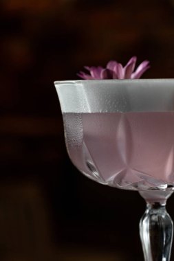 Vermutlu kokteyl, sek cin, limon suyu ve şeker şurubu. Uzun bir sapın üzerinde berrak bir bardakta çiçek ve portakal cipsi ile süslenmiş. Tahta bir yüzeye çık..