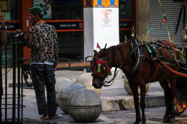 Yogyakarta, Endonezya 23 Ekim 2022. Jalan Malioboro 'ya park etmiş faytoncusu olan ve yolcu bekleyen Andong ya da at arabası. Genelde Yogyakarta 'ya tatile giden turistler kullanır..