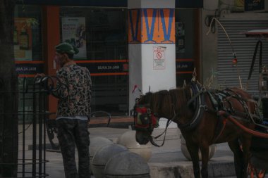 Yogyakarta, Endonezya 23 Ekim 2022. Jalan Malioboro 'ya park etmiş faytoncusu olan ve yolcu bekleyen Andong ya da at arabası. Genelde Yogyakarta 'ya tatile giden turistler kullanır..