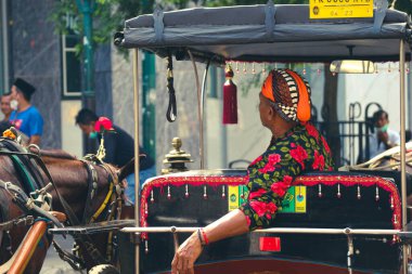 Jalan Malioboro, Yogyakarta 'da bir araba ya da Andong sürücüsü var. Tipik Cava batik kıyafetleri ve beyaz şapkalarıyla..