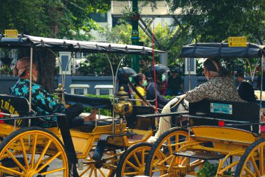 Jalan Malioboro, Yogyakarta 'daki vagon veya Andong sürücülerinin yan görüntüsü. Tipik Java batik kıyafetleri ve Blangkon şapkalarıyla. Yolcu beklerken konuşuyorlardı..