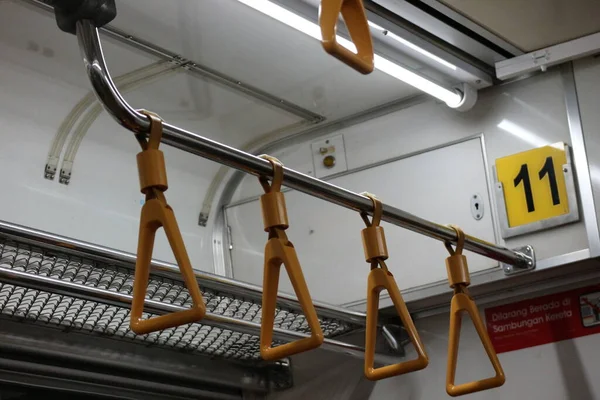The hand handle or handgrips or handrails of commuter line passengers swaying due to the movement of the train. The train is empty with no passengers.