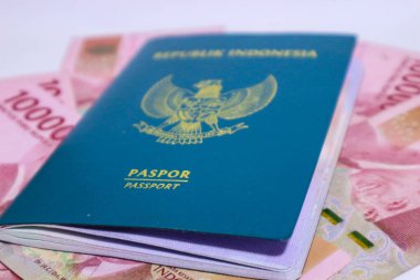 Arkaplanı 100.000 rupia olan Endonezya yeşil pasaportu. Bu pasaport yurtdışına giden Endonezya vatandaşları için bir kimlik. Endonezya parası rupiadır..