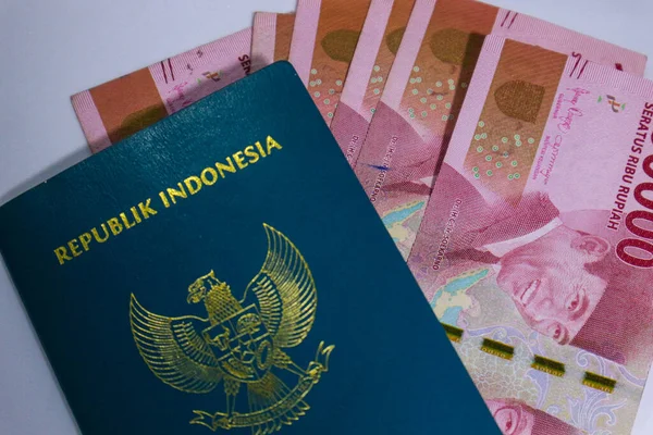 Indonesian green passport with a collection of hundred thousand rupiah as the background. This passport is an identity for Indonesian citizens who are going abroad. Indonesian currency is rupiah.