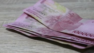 Birkaç yüz bin rupiah banknot şeklinde rüşvet alan bir kişinin iş ve finans sektörünün video çizimi. Bir el, ahşap bir masadan para alırken görülüyor..