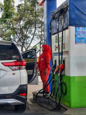 Batı Java, Endonezya Temmuz 2022. Bir Pertamina kadın memuru arabaya yakıt ikmali yapıyor. Fotoğraf Purwakarta 'daki Pertamina' ya ait bir benzin istasyonundan..