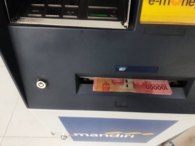 Cakarta, Endonezya Temmuz 2022. Otomatik Teller Machine 'den ya da Bank Mandiri' den birkaç yüz bin rupiah 'lık banknot geldi. Bank Mandiri Endonezya 'nın en büyük bankalarından biridir..
