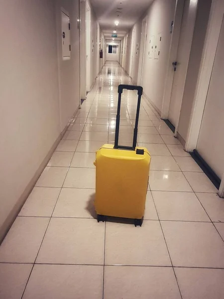 A small suitcase with a yellow color. This suitcase was placed in a hallway of the apartment.