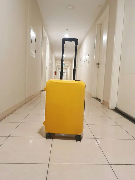 A small suitcase with a yellow color. This suitcase was placed in a hallway of the apartment.