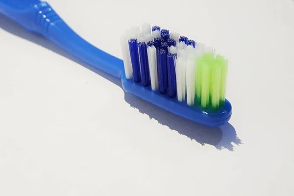 用了好几次的塑料牙刷的孤立的白色照片 这把牙刷有一个蓝色的手柄 刷子由绿色 白色和蓝色组成 — 图库照片