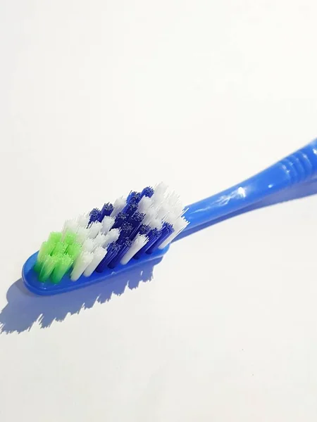 数回使用されているプラスチック歯ブラシの隔離された白い写真 この歯ブラシは青と緑 白と青で構成されたブラシ付きハンドルを持っています — ストック写真