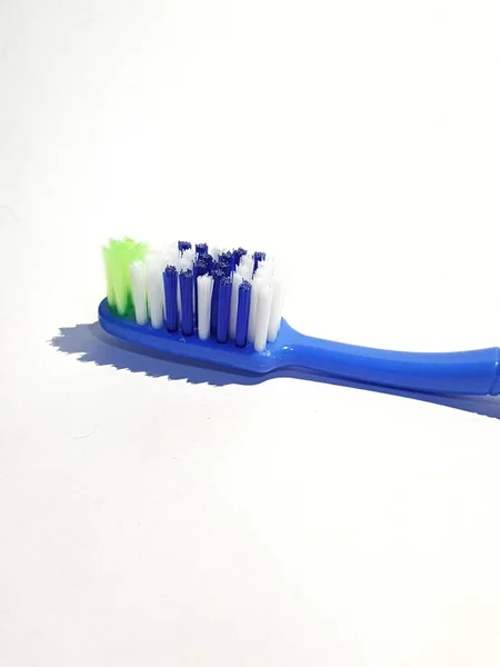 用了好几次的塑料牙刷的孤立的白色照片 这把牙刷有一个蓝色的手柄 刷子由绿色 白色和蓝色组成 — 图库照片