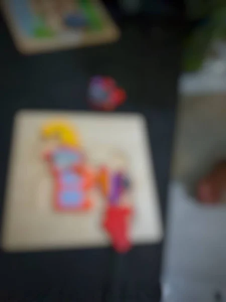 Defocused blurry shot of a boy\'s hand holding a wooden puzzle toy.