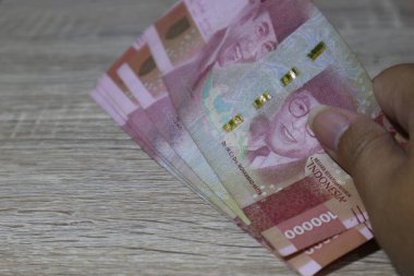Birkaç yüz bin rupiah banknot ahşap bir masaya yerleştirildi..