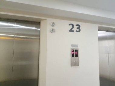 Dairenin 23. katının lobisinde yer levhalarını ve asansör kapısını görebilirsiniz..