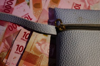 Üstüne birkaç yüz bin rupia banknotunun saçıldığı mavi bir cüzdan ya da mavi deri bir kese. Şablon geçmişiniz ya da moda, iş ve finansla ilgili haberler için mükemmeldir..