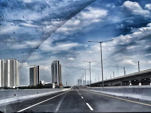 Cakarta, Endonezya Temmuz 2022. Jakarta Cikampek Yükseltilmiş Toll Yolu üzerindeki atmosfer ve manzara, veya Muhammed Bin Zayed Toll Yolu (MBZ) olarak da bilinir. Etrafında yüksek binalar, güzel mavi gökyüzü ve beyaz bulutlar var..