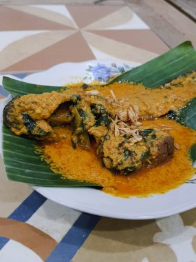 Muz yapraklı bir tabakta yayın balığı mangut servisi yapılır. Pirincin üstüne kızarmış soğan serpilmiş. Yendiğinde tadı daha lezzetli olsun diye..