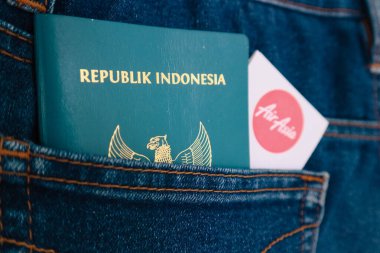 Temmuz 2022 'de Endonezya. Endonezya vatandaşlığı pasaportu ve Air Asia Havayolları 'nın kot pantolon cebinde biniş kartı. Bu fotoğraf yurt dışına seyahat etmenin bir göstergesi olarak uygundur..