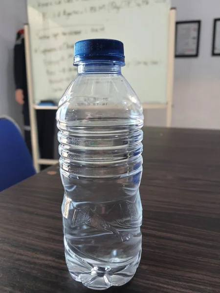 Small bottle of mineral water on a table, unlabeled.