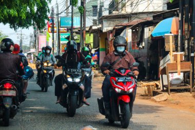 Cakarta, Endonezya Kasım 2022. Jakarta 'nın varoşlarındaki işlek bir caddede araba süren bir motosikletlinin ön görüntüsü.